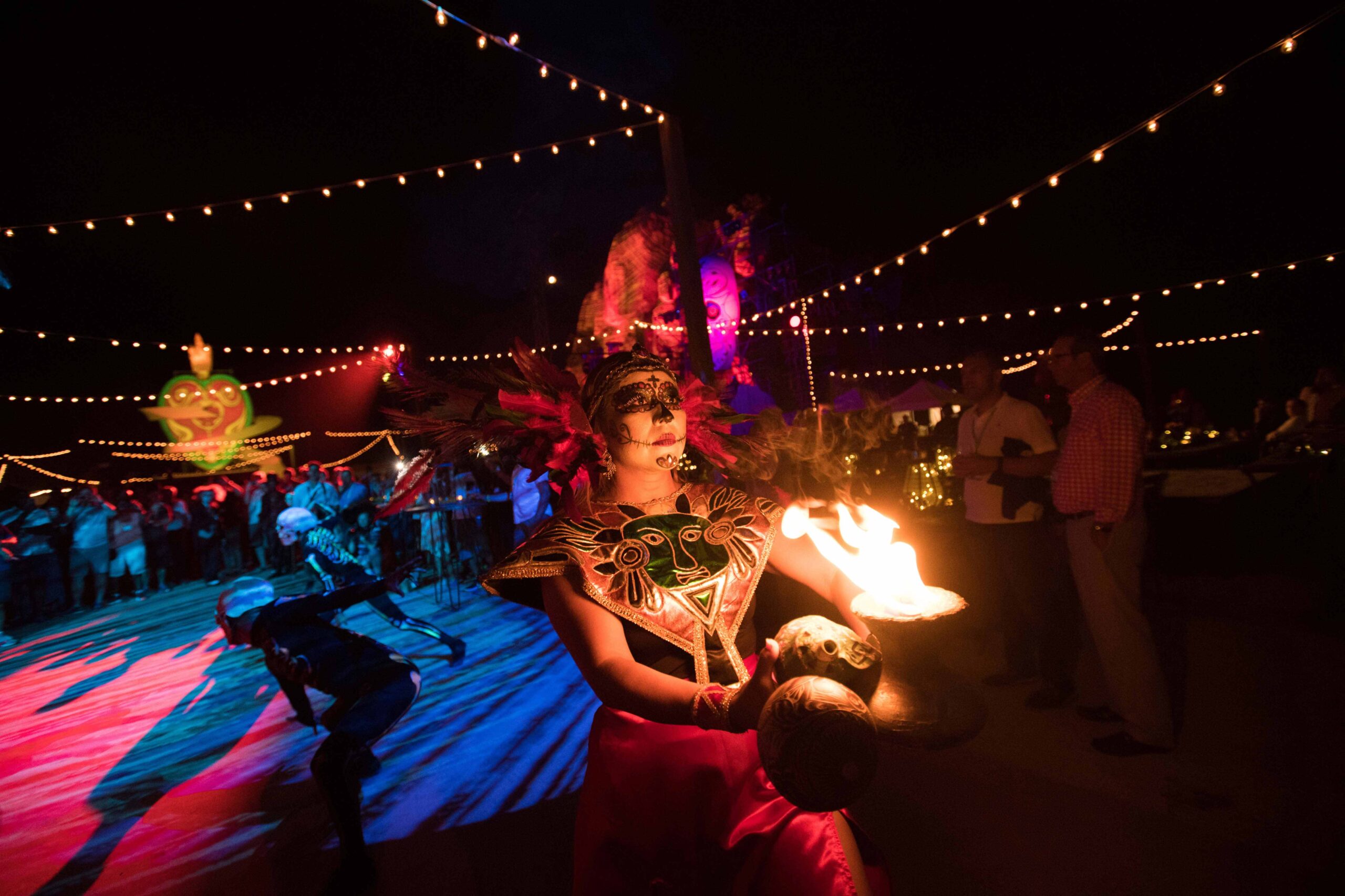 A live Day of the dead themed performance at night features a women with a costume carrying a torch.