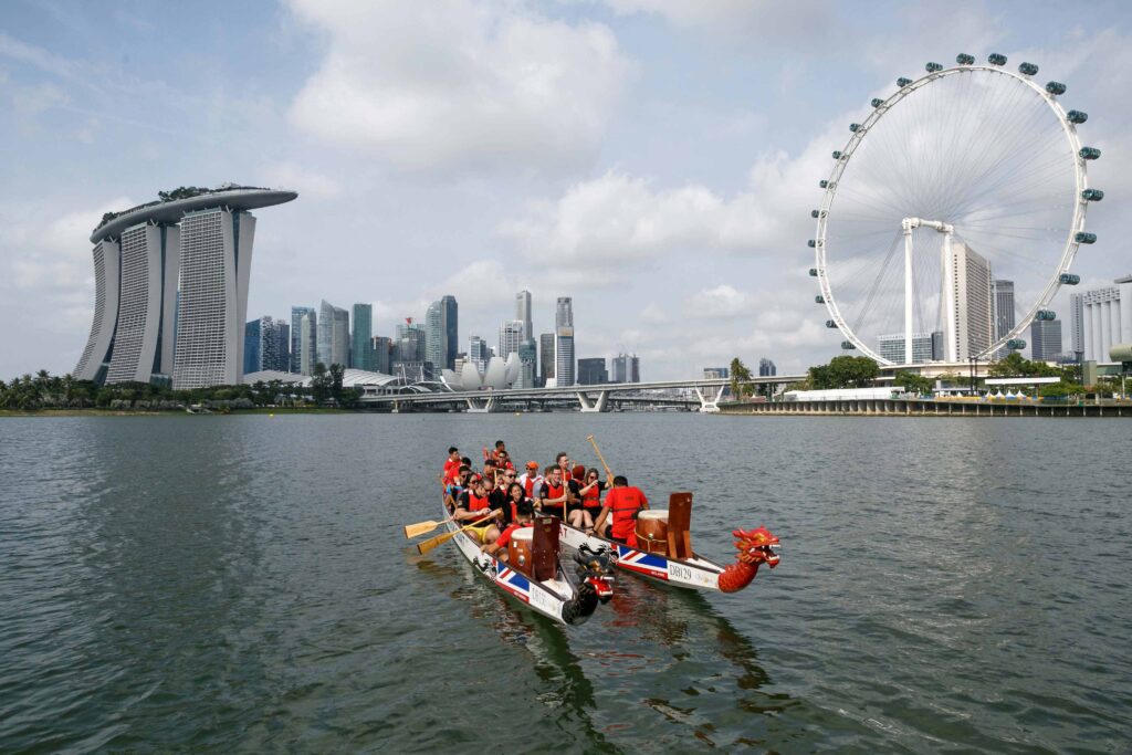 Attendees on a company retreat in Singapore enjoy a boat ride with landmarks in the background