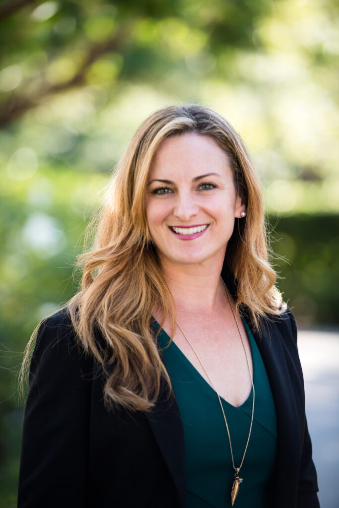 Woman wearing a green inner shirt and black blazer while posing for a professional headshot