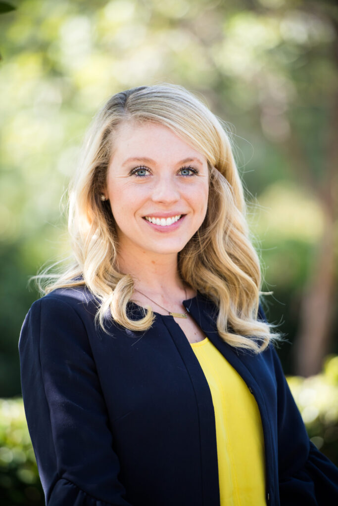 Woman wearing a yellow inner shirt and dark blue blazer while posing for her professional headshot