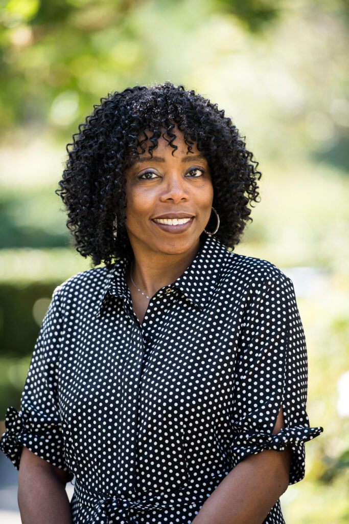 Woman wearing a white and black polka dot dress while posing for her professional headshot 