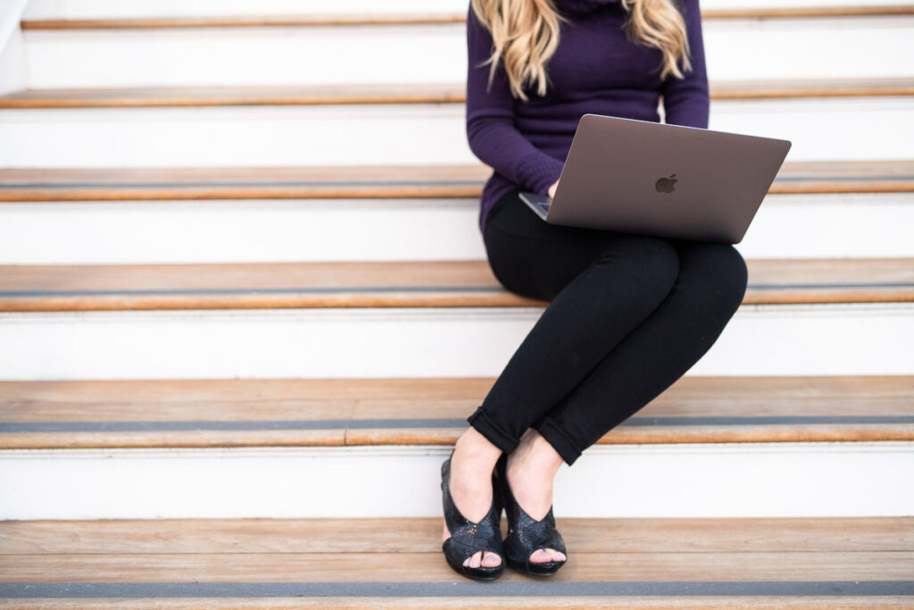 Woman sitting on the stairs while typing on her laptop