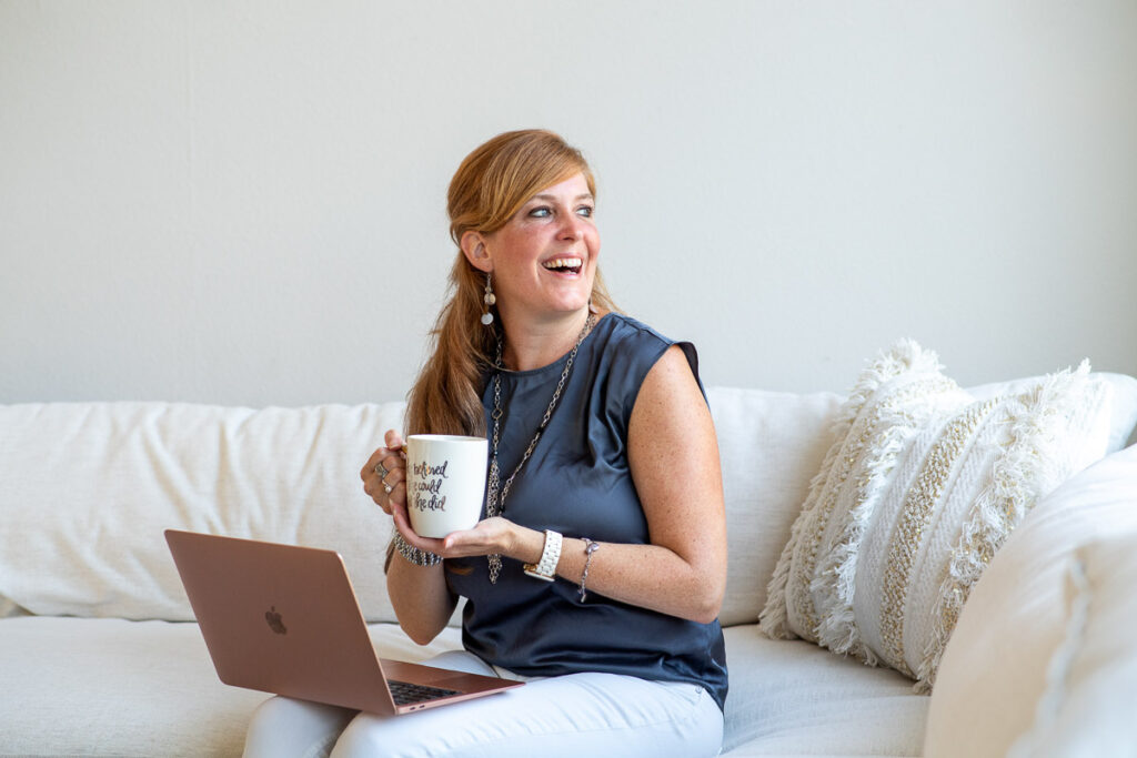 Woman wearing a blue sleeveless top, smiling while holding a cup of coffee