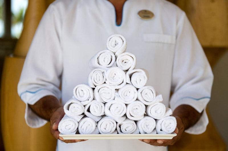 Man holding a tray of piled up folded white towels