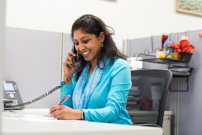 Woman happily taking a phone call while writing down notes