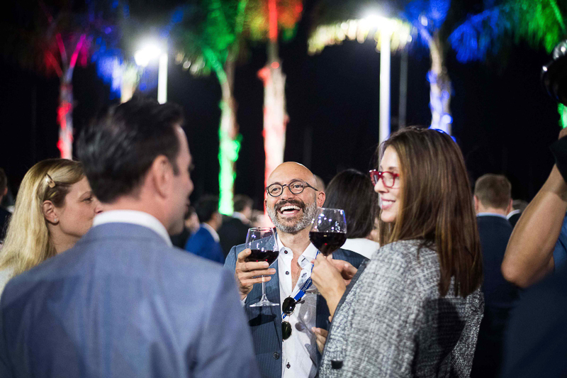 Group of people enjoying an event, while holding wine glasses