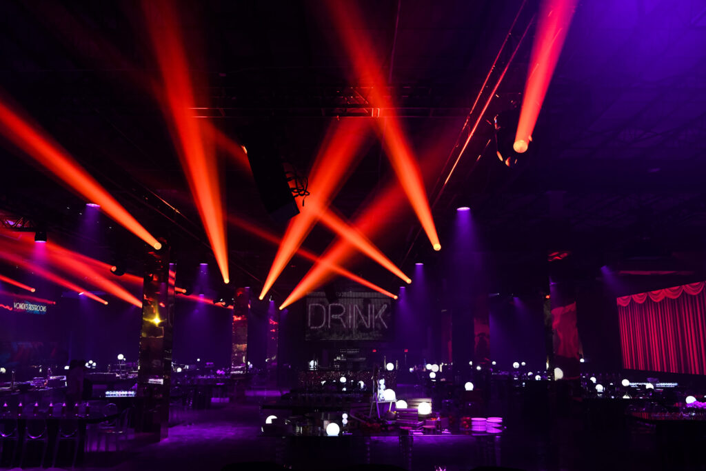 Event venue with red lights on the ceiling and prepared tables and chairs