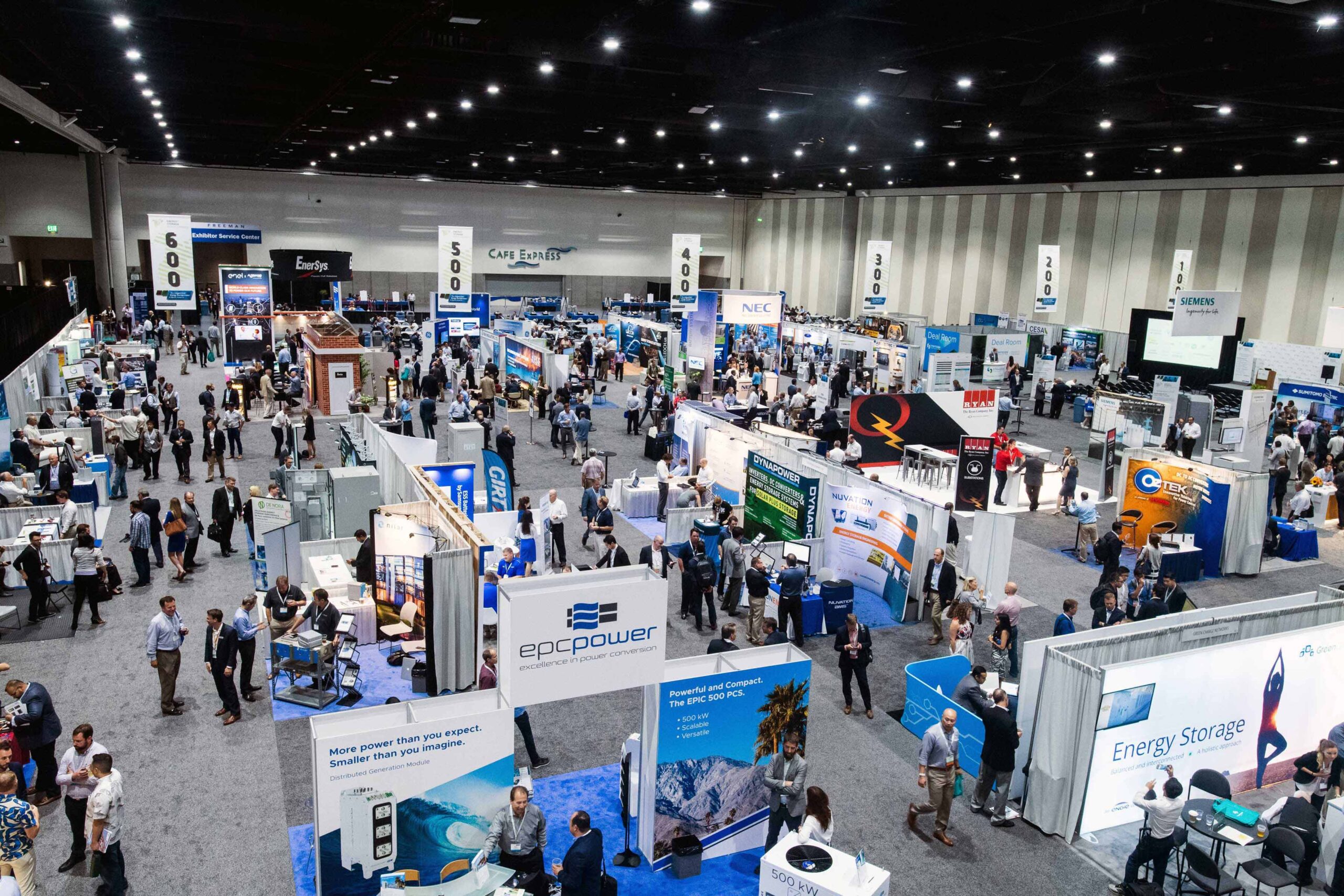 A bustling trade show floor filled with booths, banners, and attendees networking and exploring exhibits