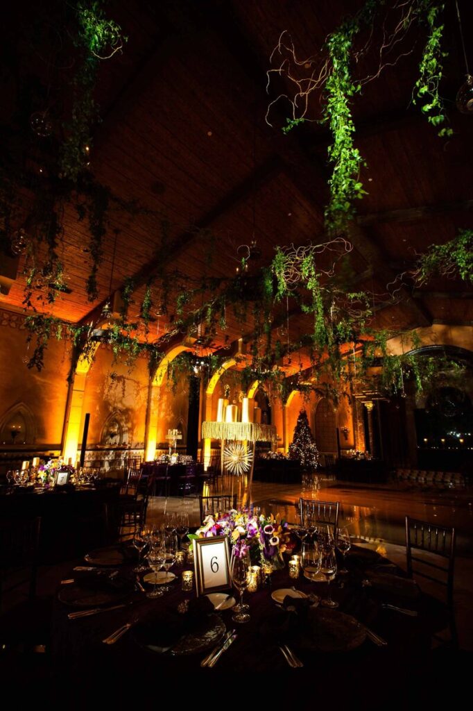 An enchanting wedding reception adorned with greenery suspended from the ceiling