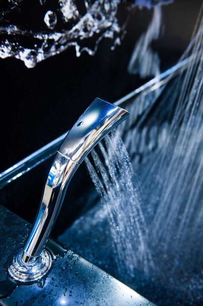 A modern chrome faucet with water flowing in a sleek, dark setting