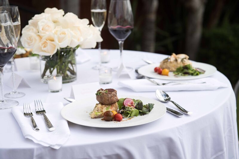 Elegant table setting with plated gourmet meals and wine glasses