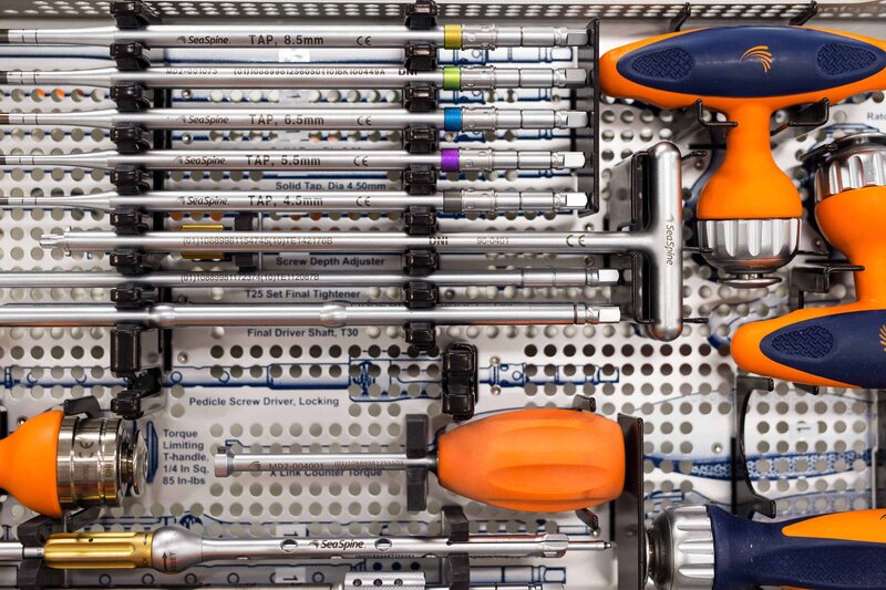 A neatly arranged toolkit with surgical or mechanical instruments and orange handles