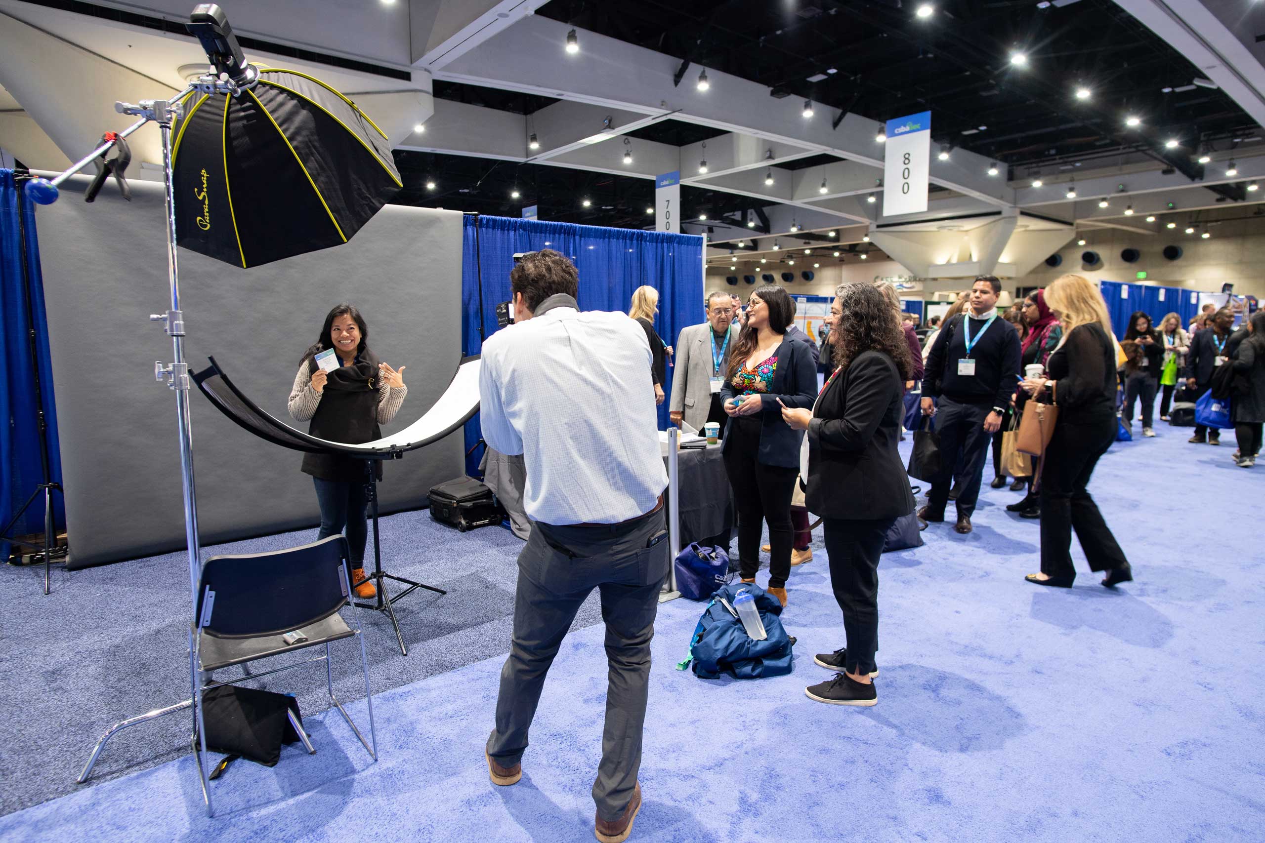 A collective of individuals encircling a large blue carpet, taking pictures on a photographer